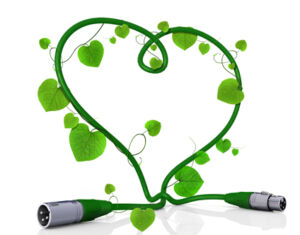 Ein grünes Buchsenkabel, von grünen Blättern umrankt, ist zu einem Herz geformt