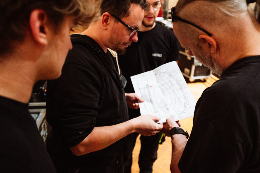 Vier Eventtechniker, die im Kreis stehen und einen Plan studieren.